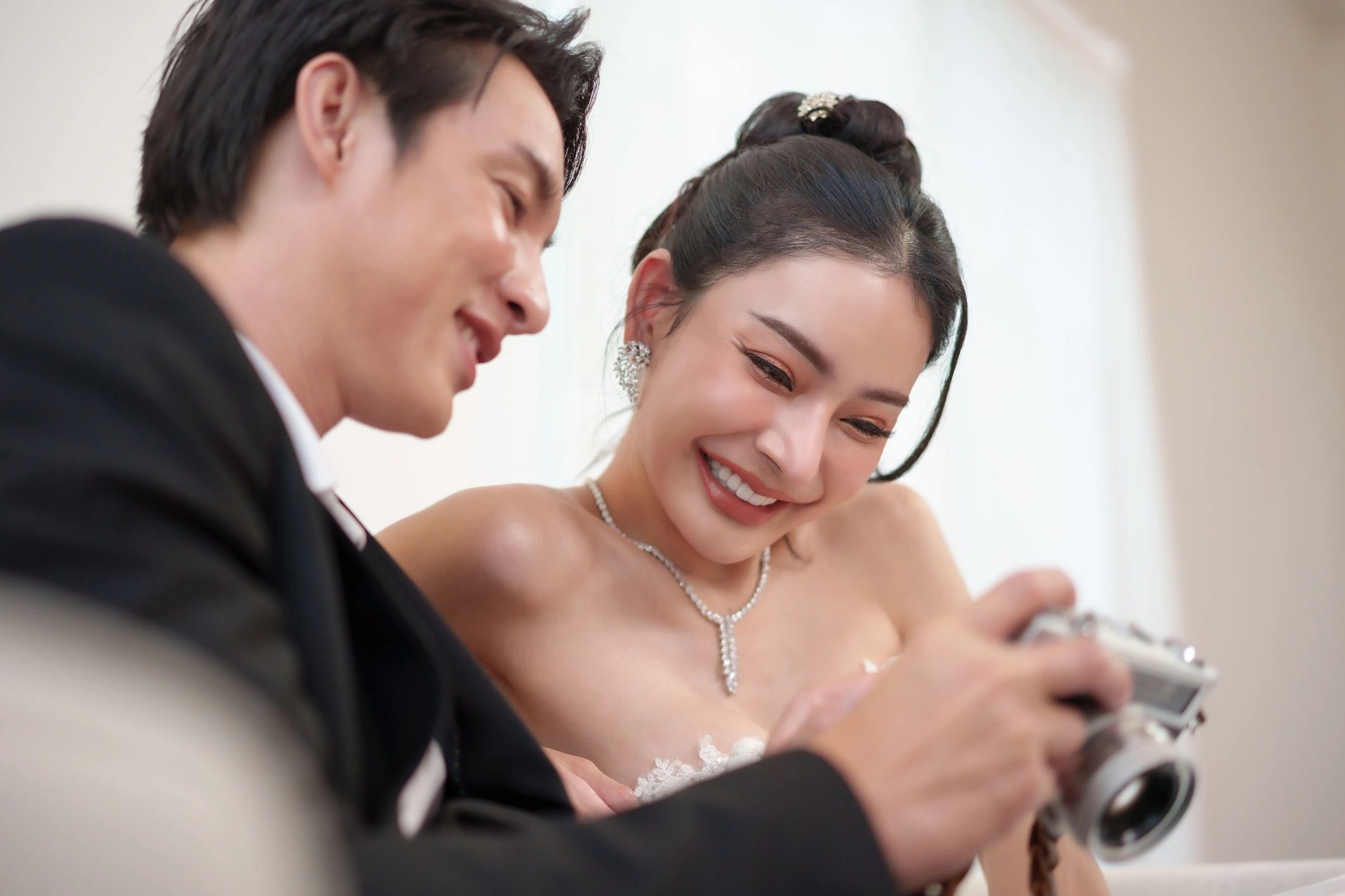 Bride and groom laughing while reviewing photos on camera